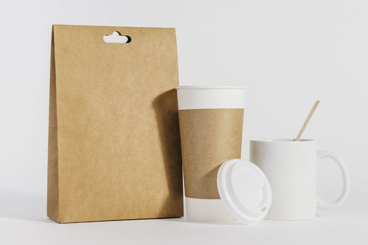 a coffee cup and paper bag sitting next to each other
